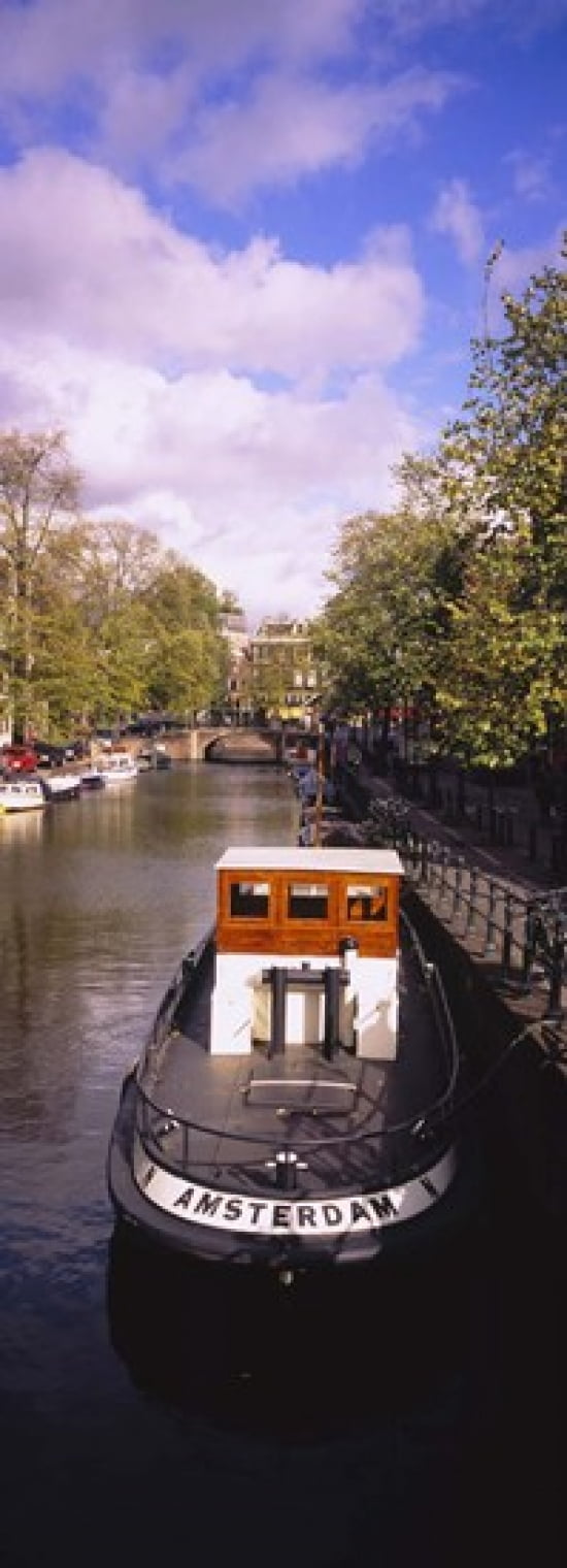 Tourboat docked in a channel Amsterdam Netherlands Canvas Art - Panoramic Images (36 x 13)