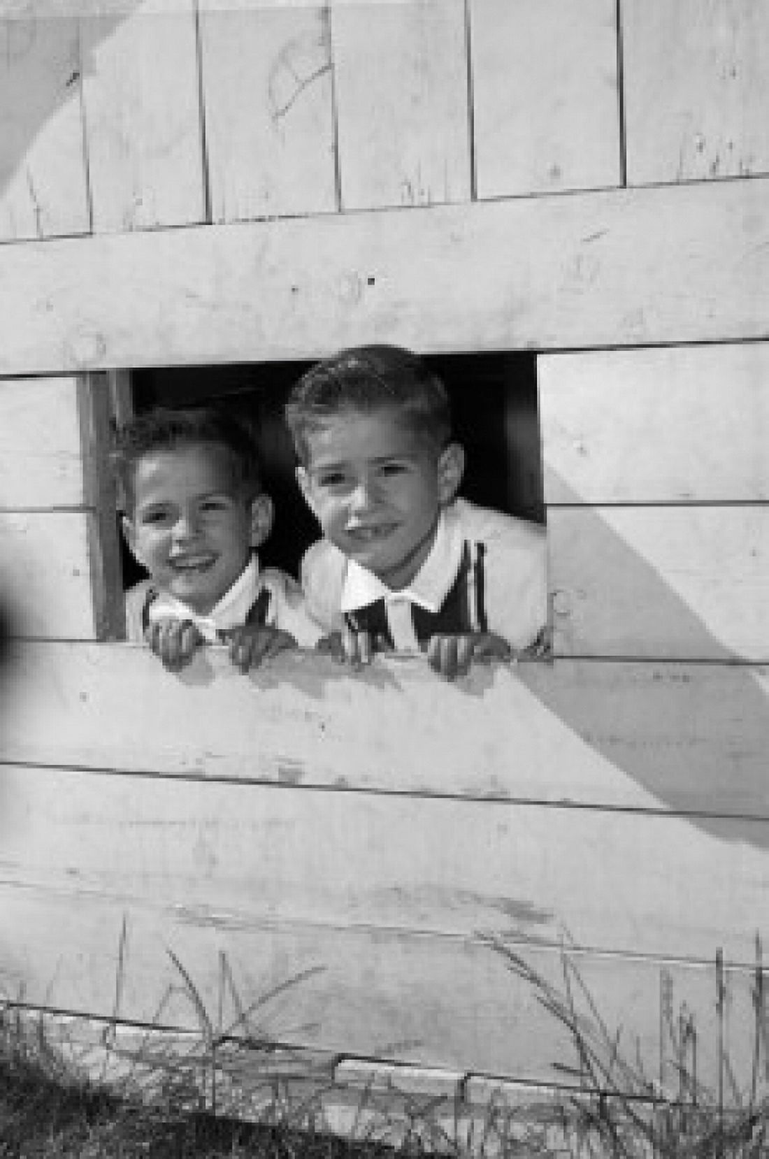 Twin brothers looking through window of wooden playhouse Canvas Art - (24 x 36)