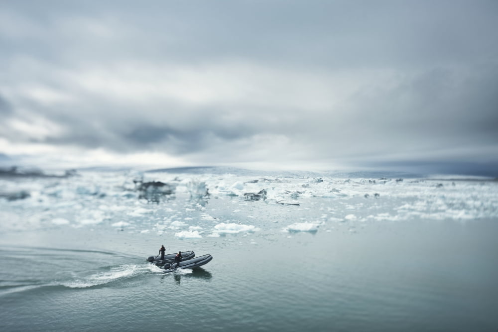 Two Men On A Nautical Vessel Driving Towards Chunks Of Ice In The Water Jokulsarlon Iceland Canvas Art - David DuChemin Design Pics (19 x 12)