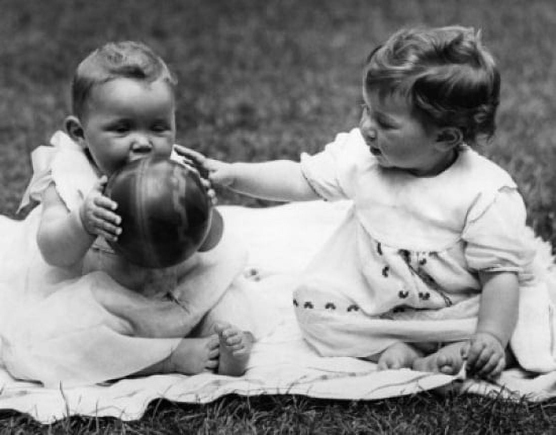 Two baby girls sitting on blanket and playing with ball Canvas Art - (24 x 36)
