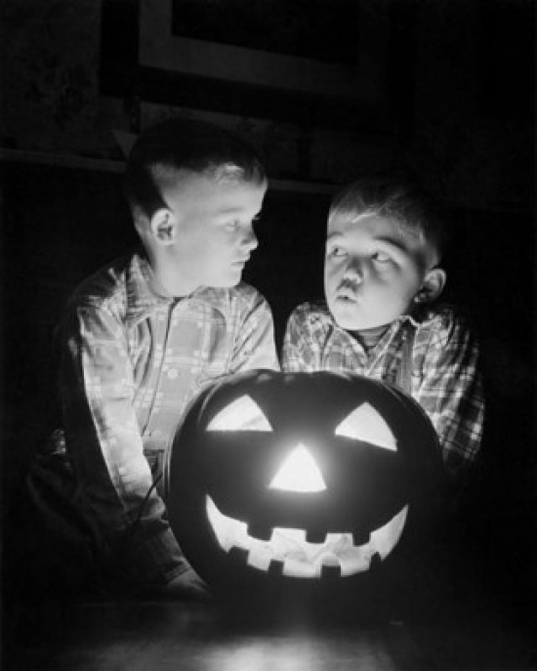 Two boys sitting behind an illuminated jack o lantern Canvas Art - (18 x 24)