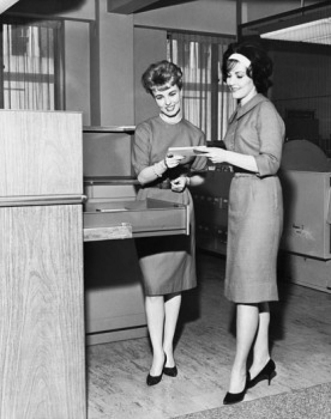 Two businesswomen taking out paper from filing cabinet Canvas Art - (24 x 36)