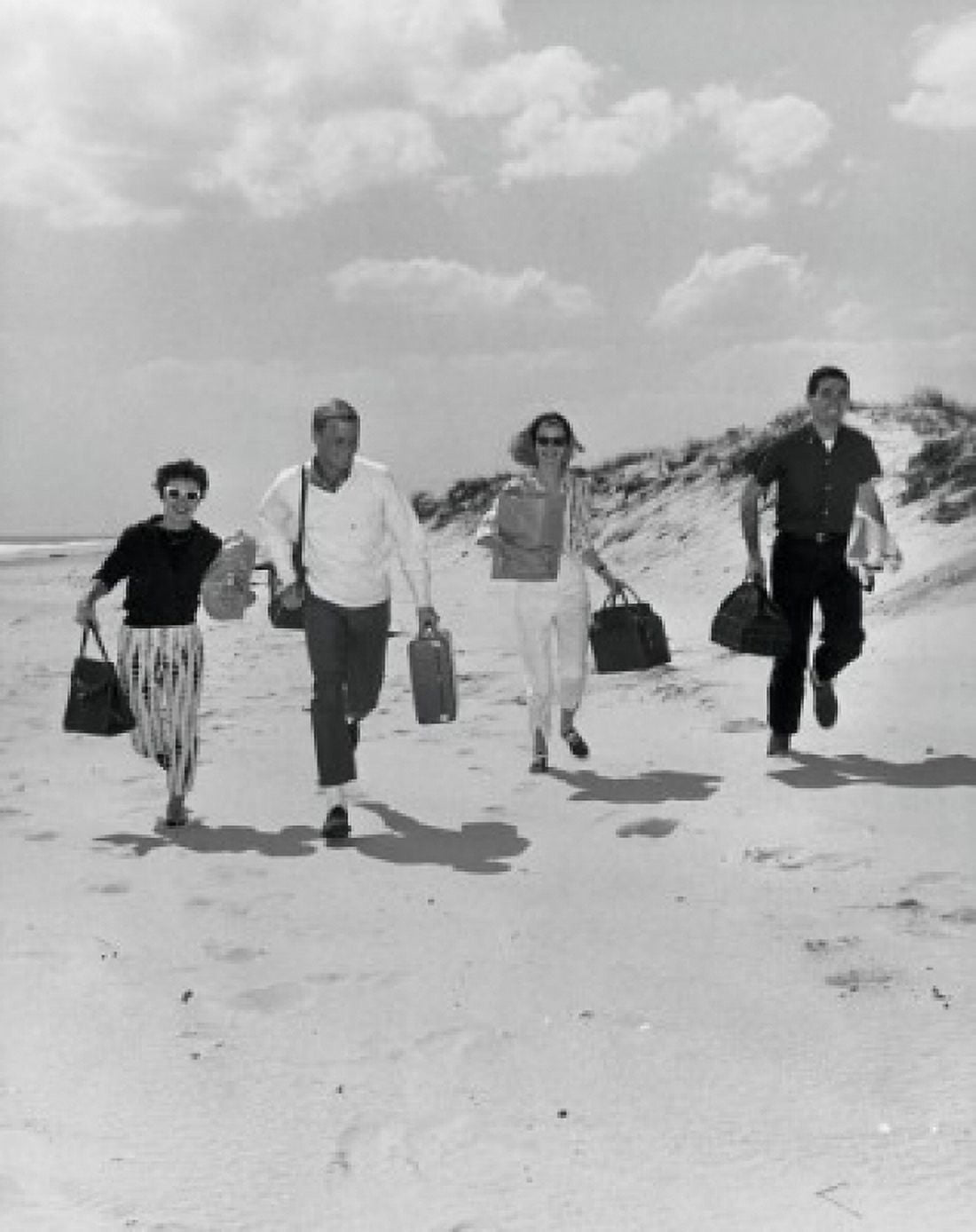 Two mid adult couples holding bags and running on the beach Canvas Art - (24 x 36)