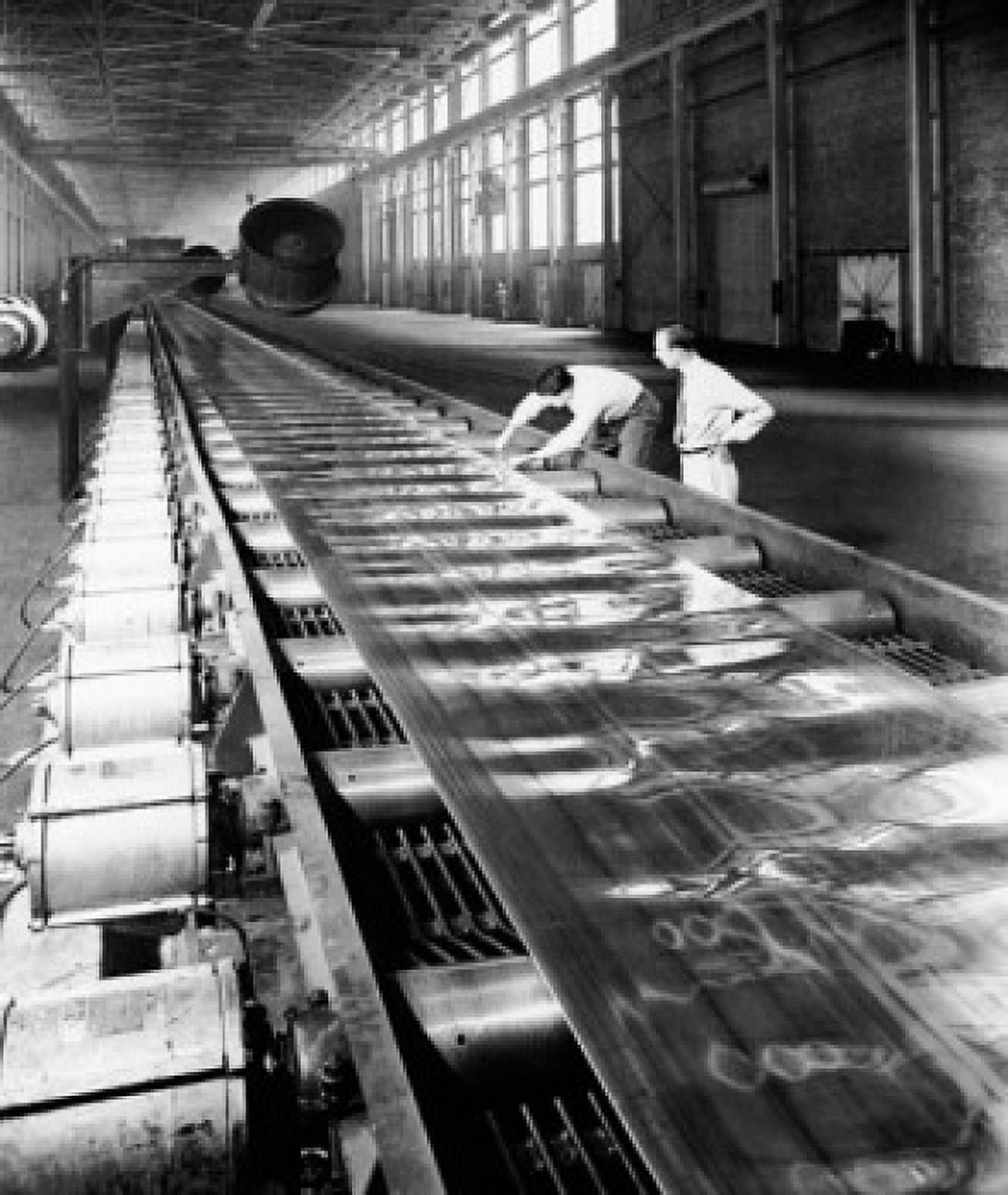 Two people examining the strip of aluminum sheet being processed through large rolling mills Canvas Art - (18 x 24)