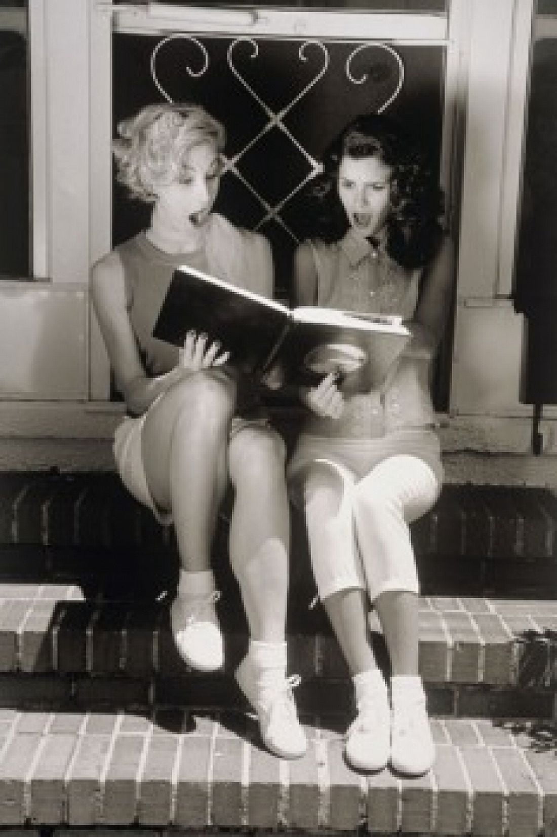 Two young women looking at photo album Canvas Art - (18 x 24)