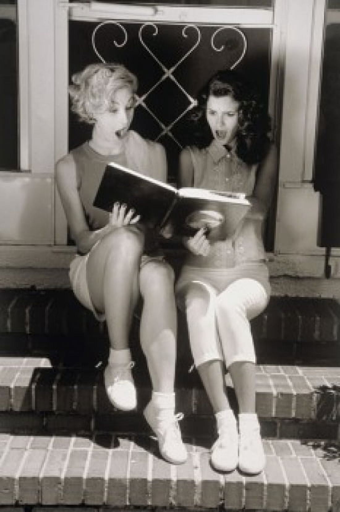Two young women looking at photo album Canvas Art - (24 x 36)