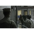 thumbnail image 1 of U.S. Sailor Stands Watch Over A Cell Block At U.S. Naval Station Guantanamo Bay Military Prison While Detainees Look, 1 of 2