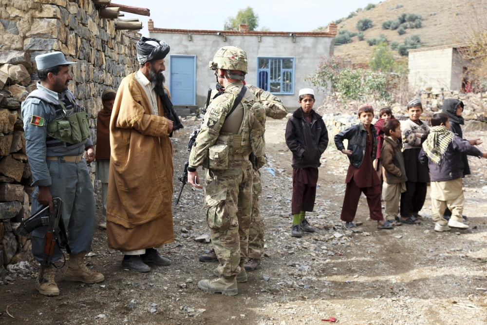 US Army Soldier and an Afghan Uniform Policeman speak with a village official Canvas Art - Stocktrek Images (35 x 23)