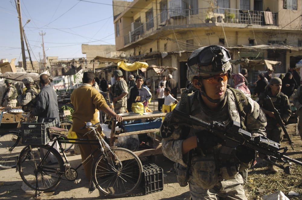 US Army Specialist moves through an open-air market during a foot patrol in Iraq Canvas Art - Stocktrek Images (34 x 23)