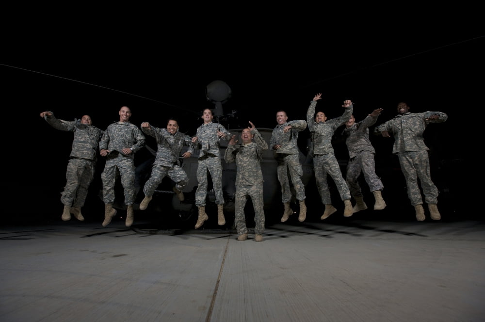 US Army pilots & crew chiefs jump for a group photo in front of their OH-58D Kiowa Canvas Art - Terry MooreStocktrek Images (18 x 12)