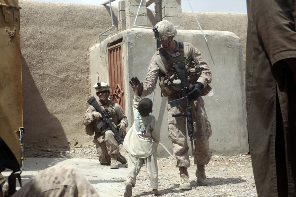 US Marine gives an Afghan child a high-five while on a patrol in Afghanistan Canvas Art - Stocktrek Images (34 x 23)