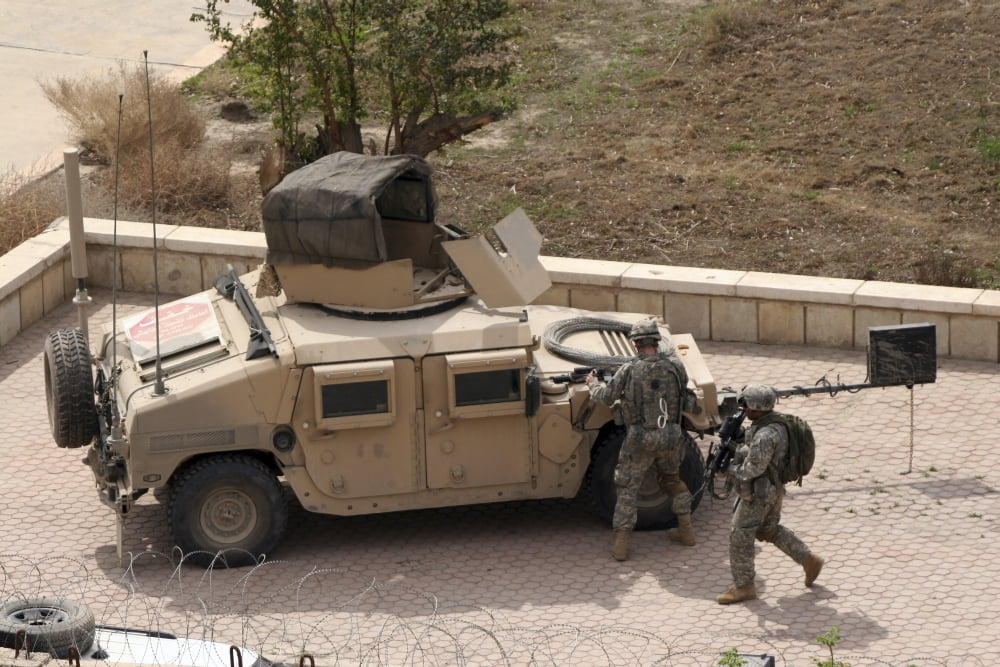 US Military soldiers take a well earned break in the foreground of the Baghdad Hotel Canvas Art - Terry MooreStocktrek Images (35 x 23)
