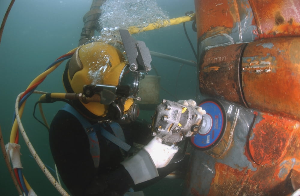 US Navy Diver uses a grinder to file down a repair patch on the submerged bow of the USS Ogden Canvas Art - Stocktrek Images (34 x 23)