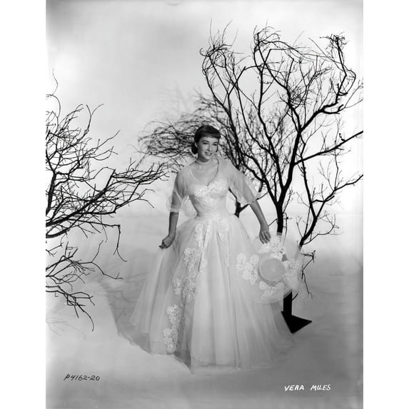 Vera Miles photographed holding an elegant designed hat, with leaveless trees, wearing a white tule ballgown, with tule quartered sleeves Photo Print (8 x 10)