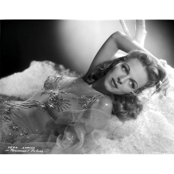 Vera Zorina laying on white, plush blankets, wearing a sweetheart, sleeveless dress, with tule overlay, beautifully decorated with amzing patterns sewn with sequins Photo Print (8 x 10)