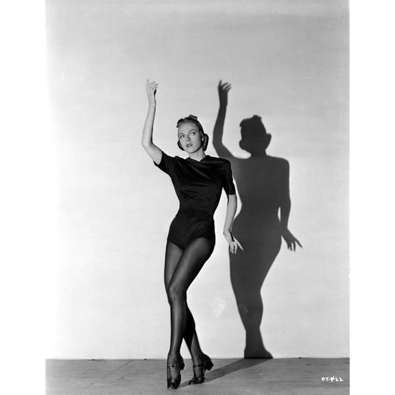 Vera Zorina wearing black leotard, black stockings, and side-clasped dance shoes, with one arm raised, and looking away from the camera Photo Print (8 x 10)