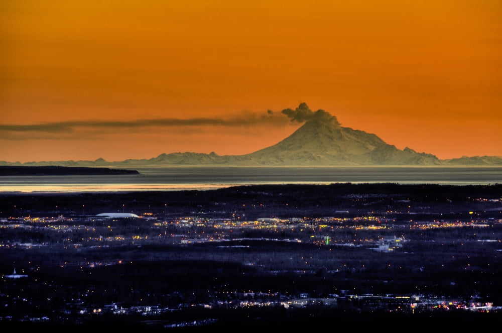 View Of The Anchorage Skyline At Sunset With Mount Redoubt Erupting In The Background Southcentral Alaska Spring Canvas Art - Michael Jones Design Pics (17 x 11)