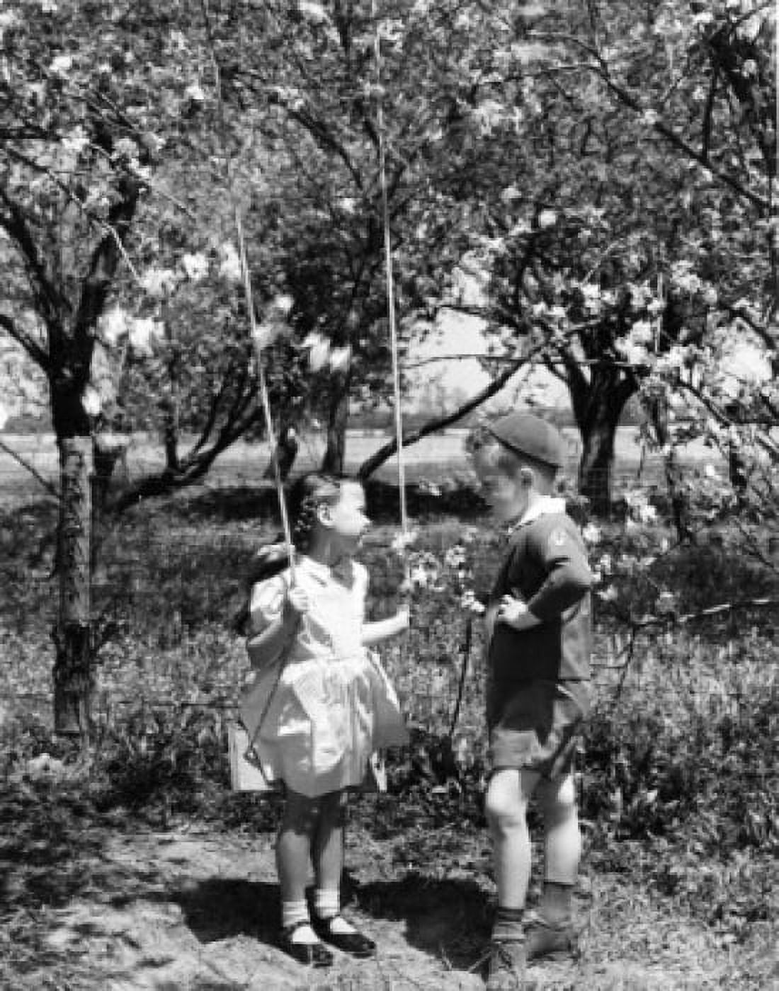 Vintage photograph of boy talking to girl standing with swing under trees in blossom Canvas Art - (18 x 24)