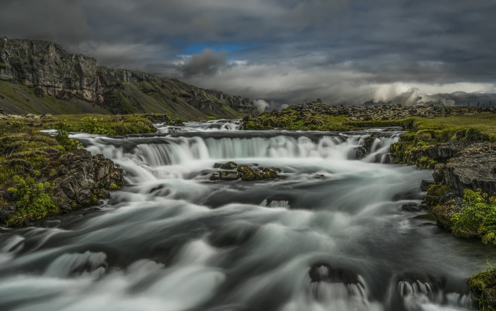 Water flowing over a rugged landscape under a cloudy sky Iceland Canvas Art - Jonathan Tucker Design Pics (19 x 12)