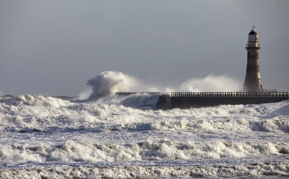 Waves Crashing Against A Pier With A Lighthouse Canvas Art - John Short Design Pics (38 x 24)