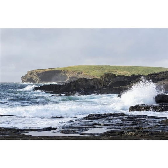 Waves crashing into rocky coast with large grassy hill and cliffs in background; Kilkee County Clare Ireland