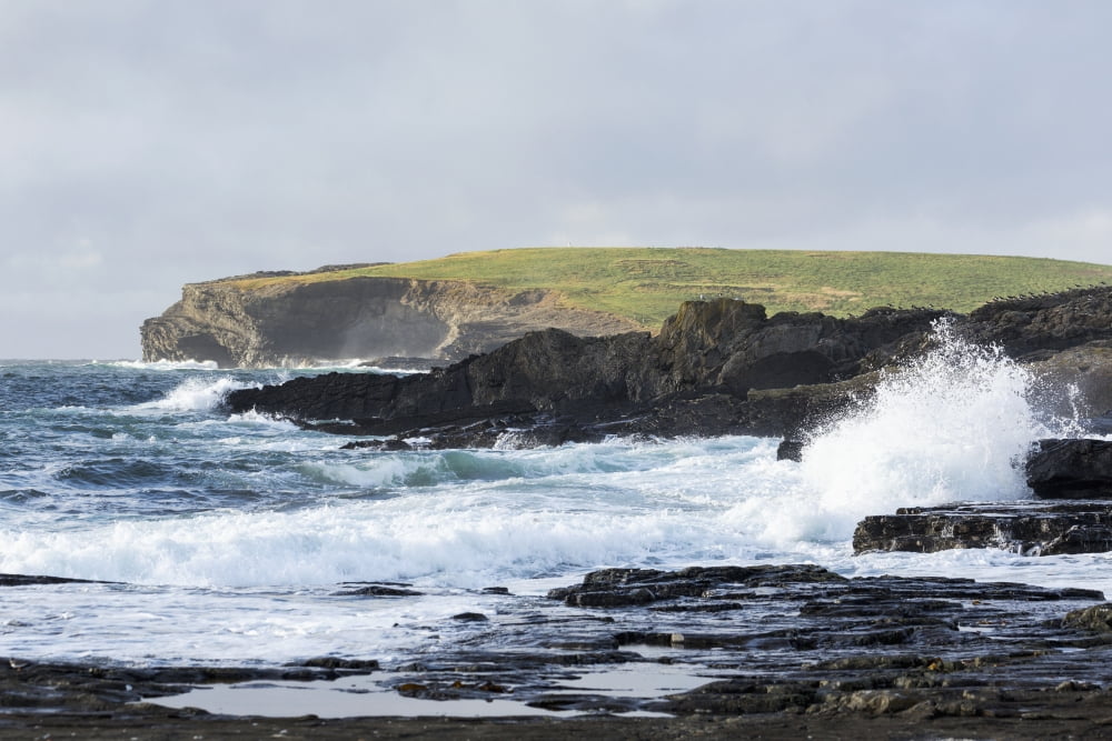 Waves crashing into rocky coast with large grassy hill and cliffs in background Kilkee County Clare Ireland Canvas Art - Michael Interisano Design Pics (19 x 12)