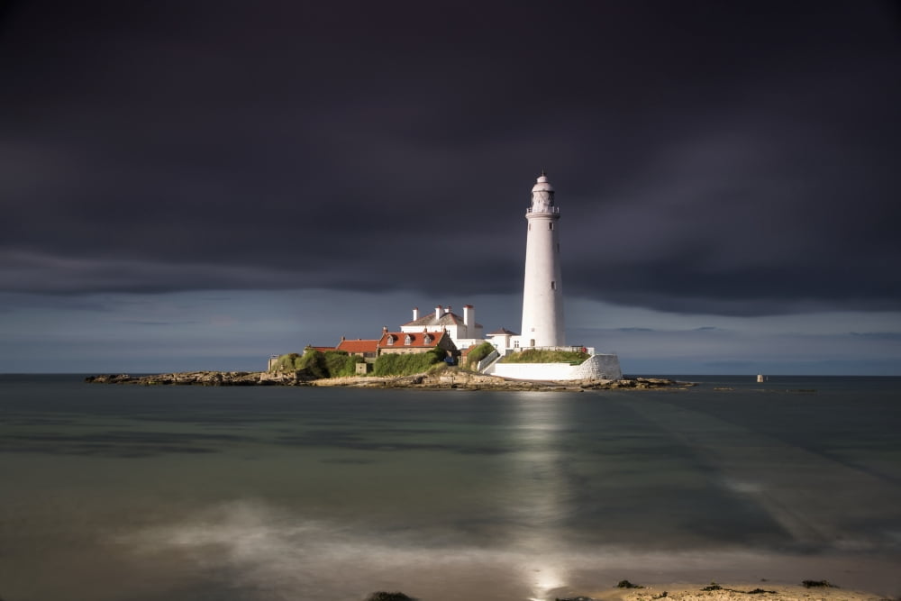 White Lighthouse Illuminated By Sunlight Under A Dark Stormy Sky St Marys Island Northumberland England Canvas Art - John Short Design Pics (38 x 24)