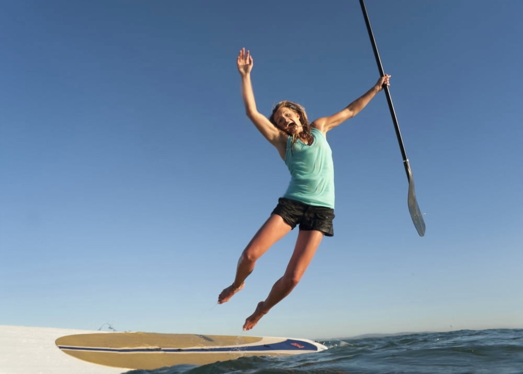 A Woman Jumps Into The Water Off A Surf Board While Holding Her Paddle In Front Of Dos Mares Beach Tarifa Cadiz Andalusia Spain Canvas Art - Ben Welsh Design Pics (17 x 12)