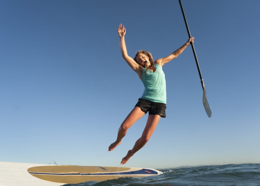 A Woman Jumps Into The Water Off A Surf Board While Holding Her Paddle In Front Of Dos Mares Beach Tarifa Cadiz Andalusia Spain Canvas Art - Ben Welsh Design Pics (34 x 24)