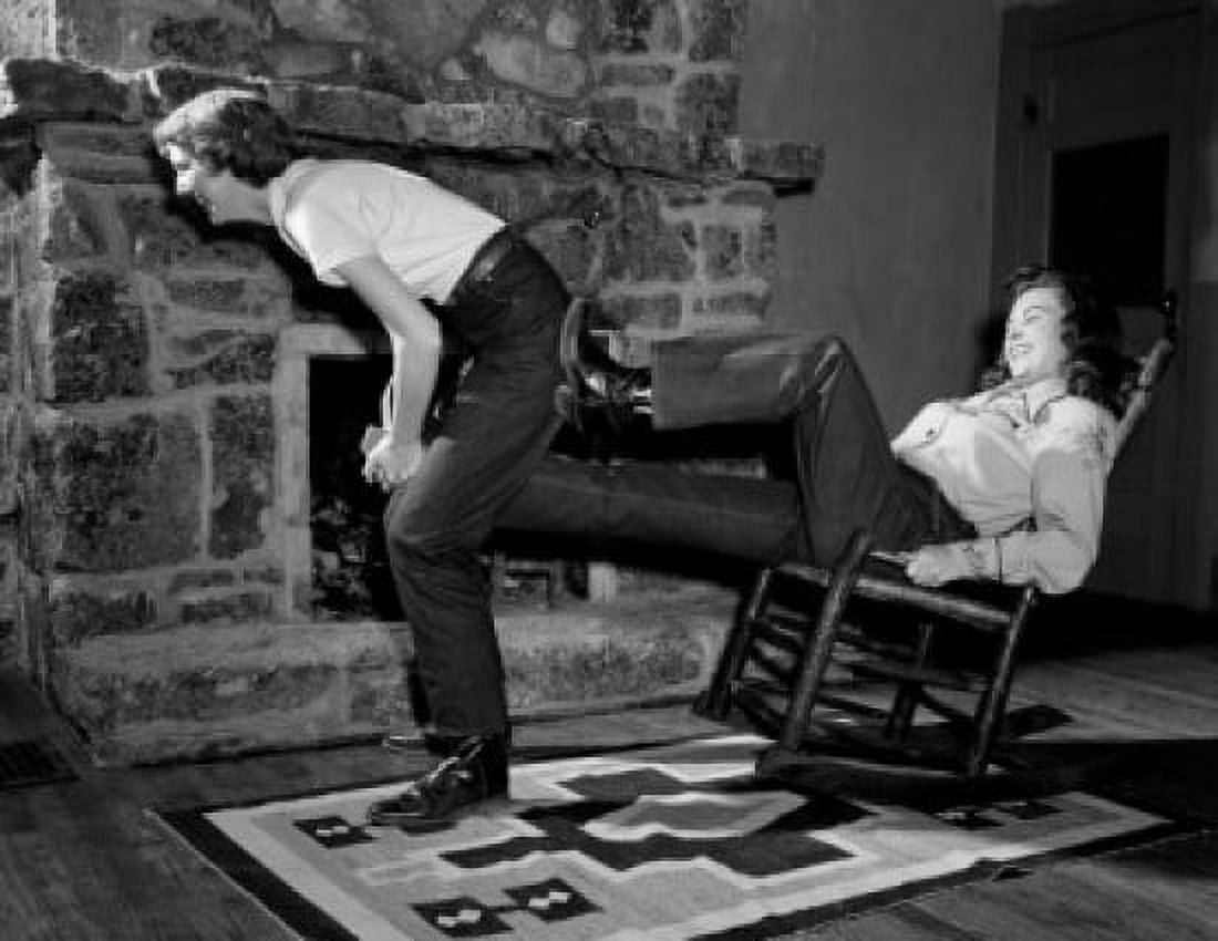 Woman pulling cowboy boot of anothers in front of fireplace Canvas Art -  (18 x 24)