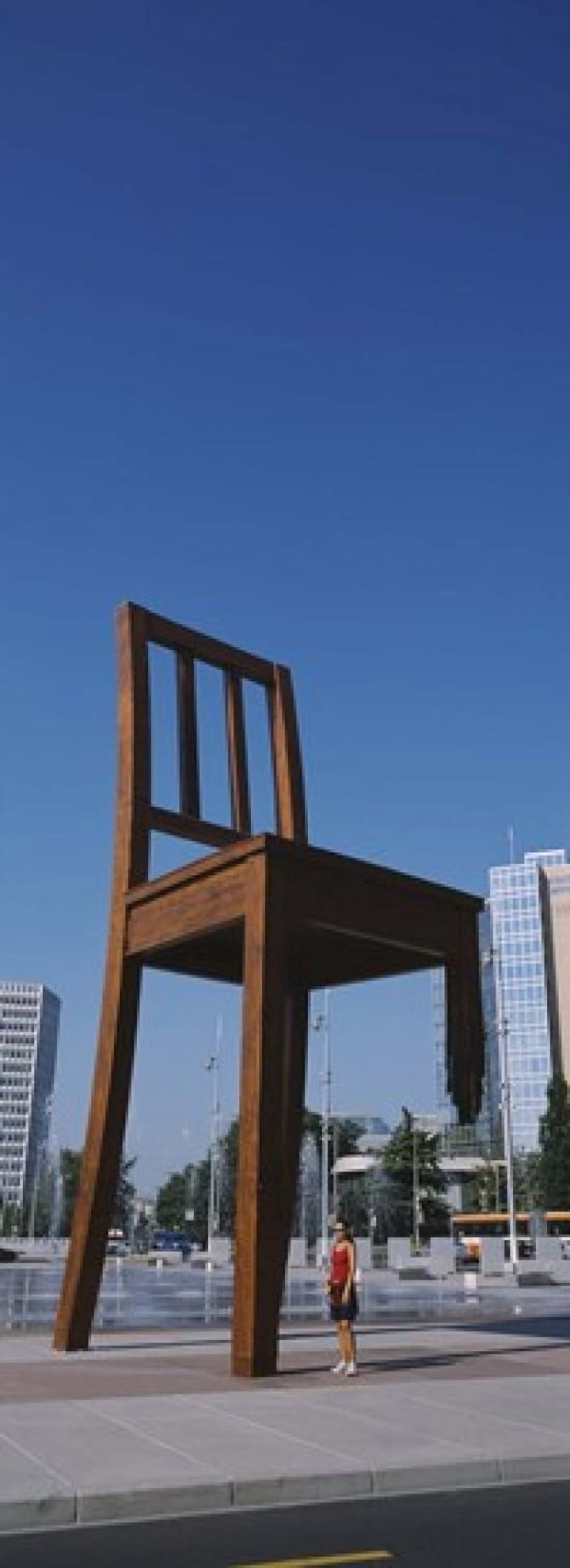 Woman standing under a sculpture of large broken chair Geneva Switzerland Canvas Art - Panoramic Images (18 x 7)