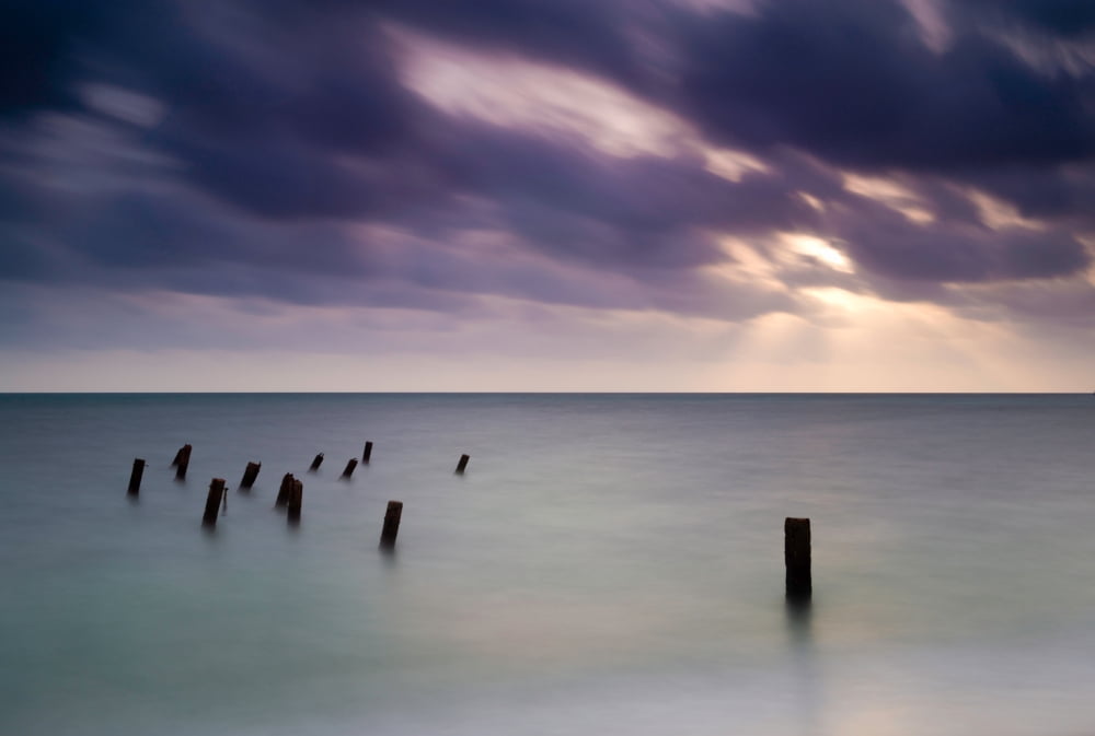 Wooden posts in sea under stormy sky at sunrise Placencia Stann Creek Belize Canvas Art - Panoramic Images (18 x 24)