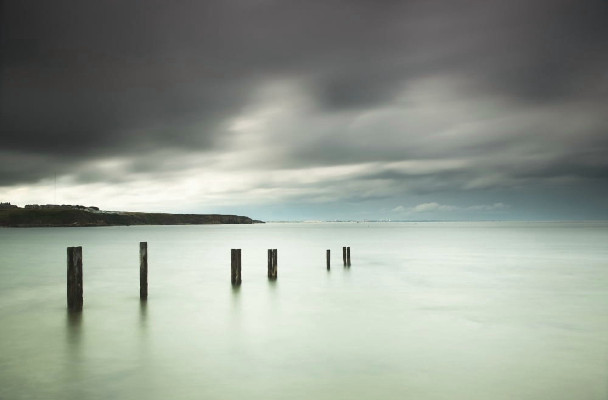 Wooden posts in a row in the shallow water along the coast under storm cloudsSt marys bay northumberland england Canvas Art - John Short Design Pics (19 x 12)