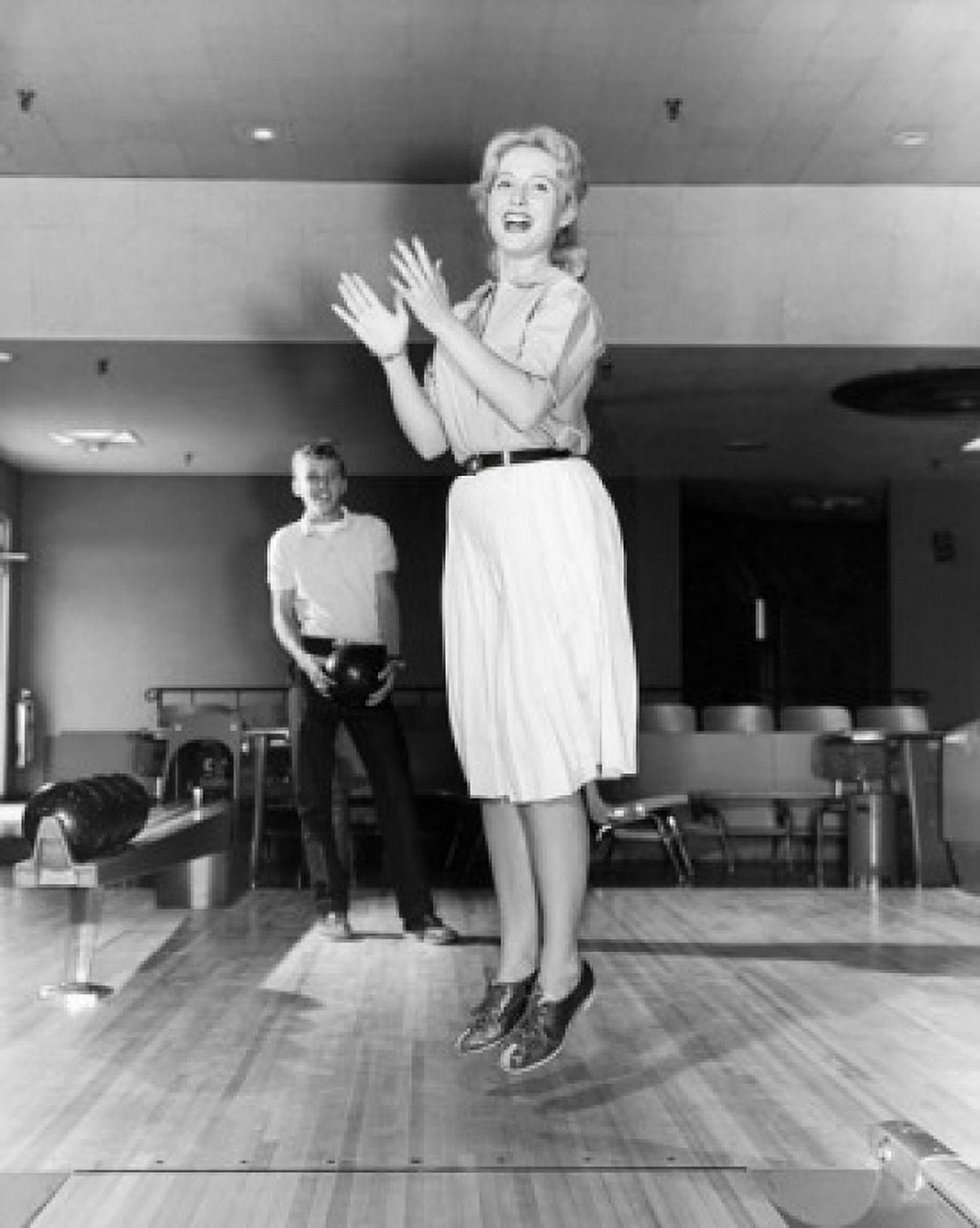 Young adult woman jumping and clapping in bowling alley Canvas Art - (24 x 36)