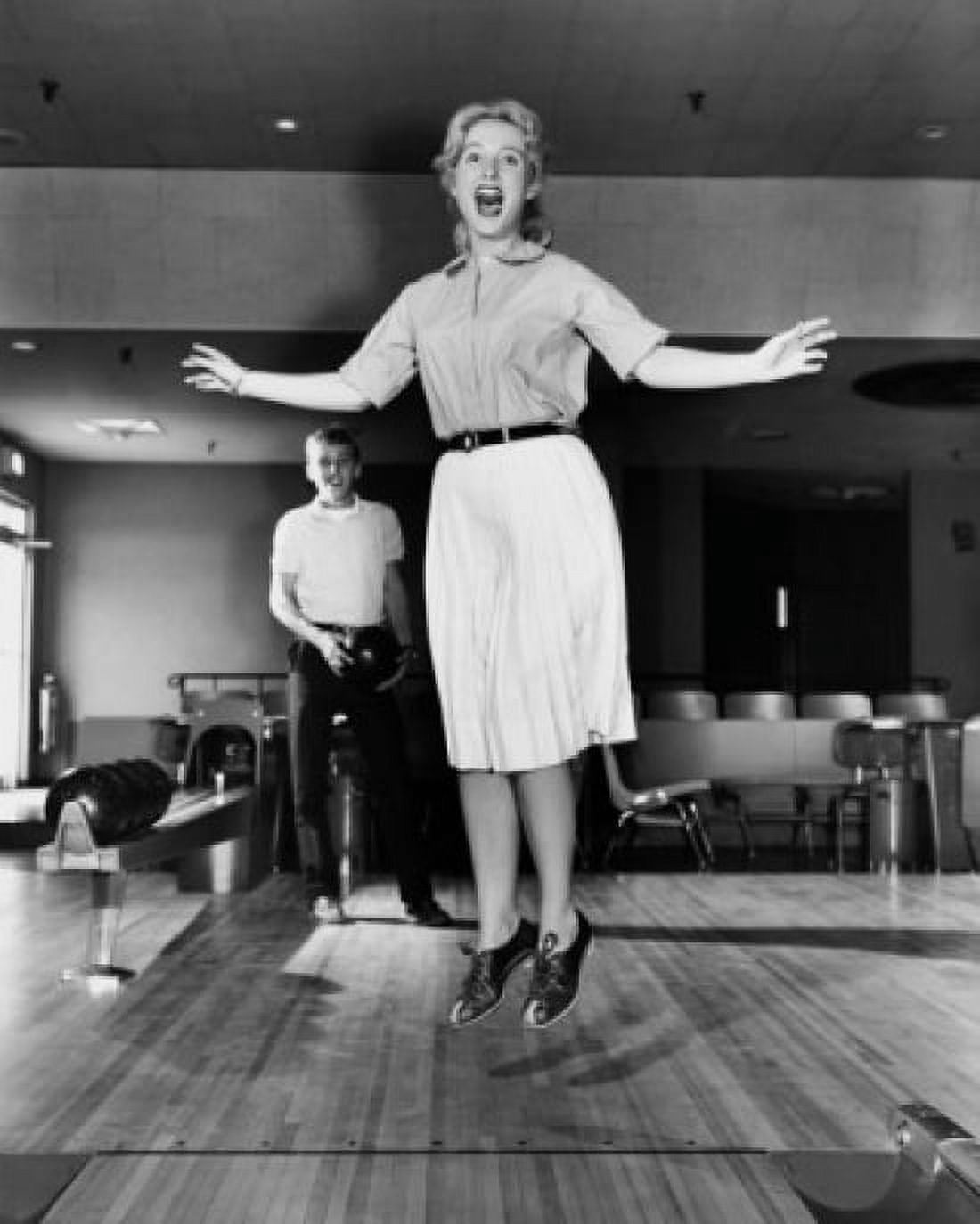 Young adult woman jumping in a bowling alley Canvas Art - (24 x 36)