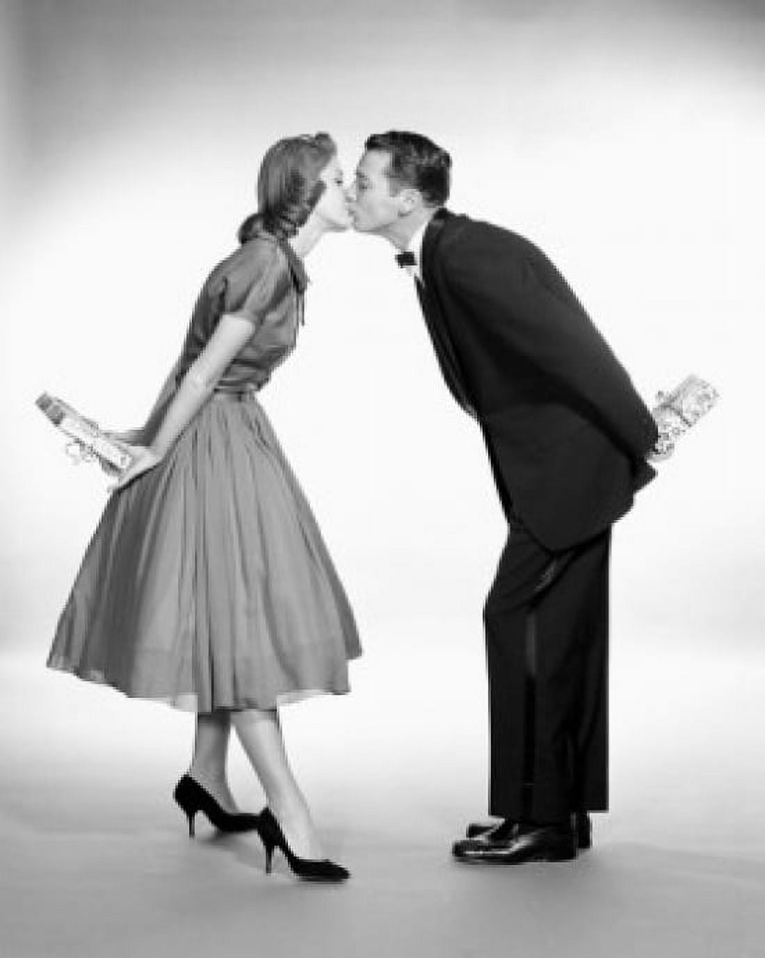 Young couple kissing while holding presents behind back Canvas Art - (24 x 36)