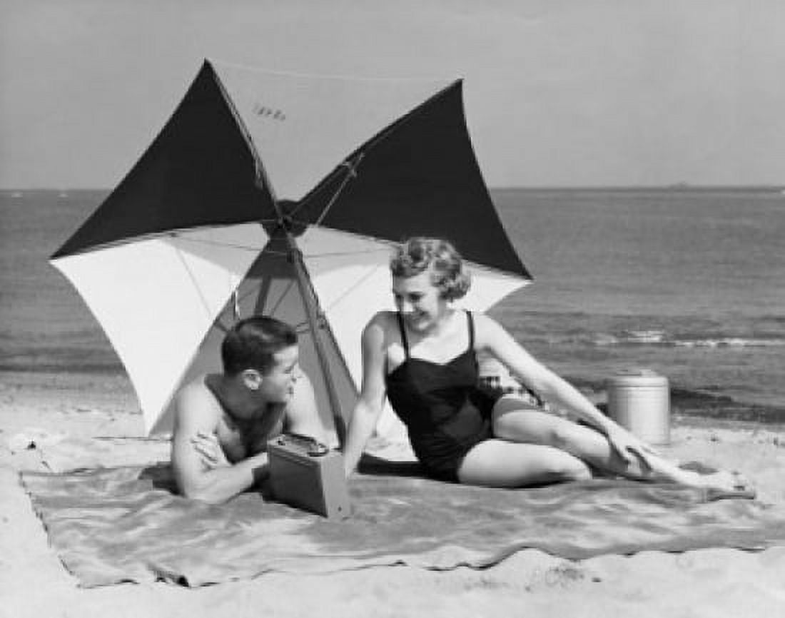 Young couple listening to radio on beach Canvas Art - (24 x 36)