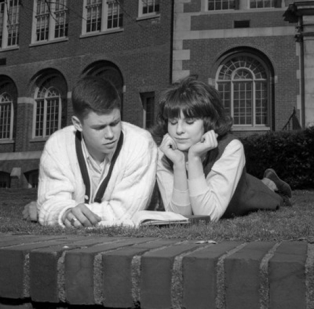 Young couple reading on grass outside university Canvas Art - (24 x 36)