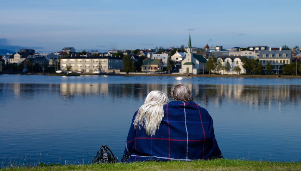 Young couple sitting by the pond (Tjornin) Reykjavik Iceland Canvas Art - Panoramic Images (24 x 14)