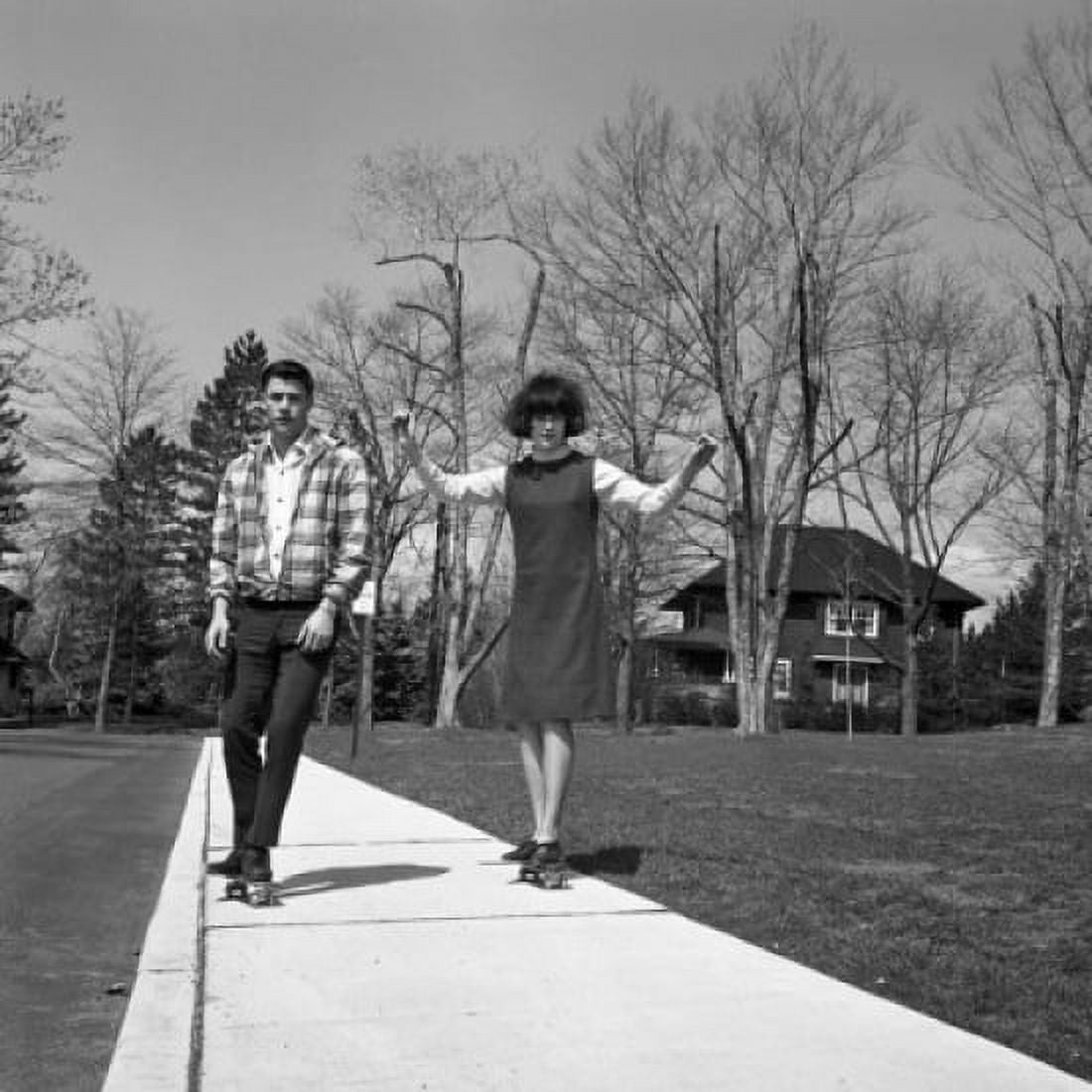 Young couple skateboarding on pavement Canvas Art - (24 x 36)