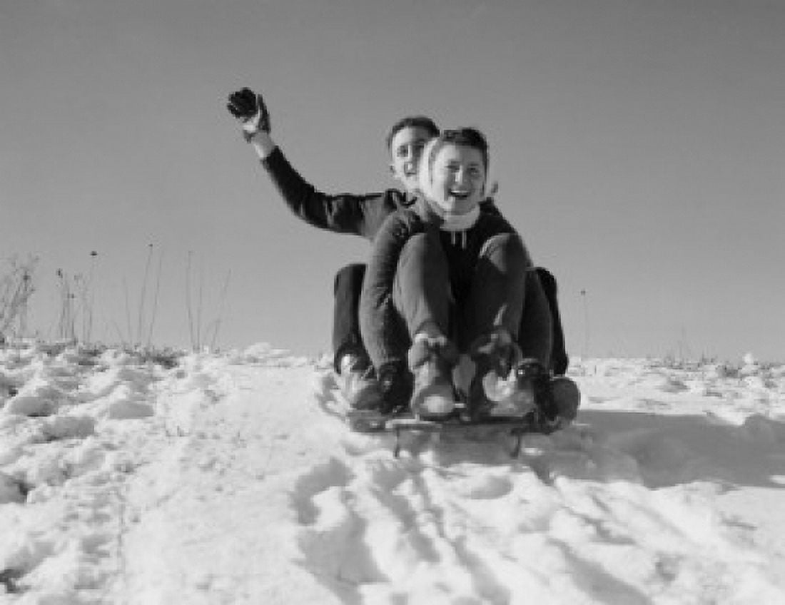 Young couple sledding down snowy hill Canvas Art - (24 x 36)