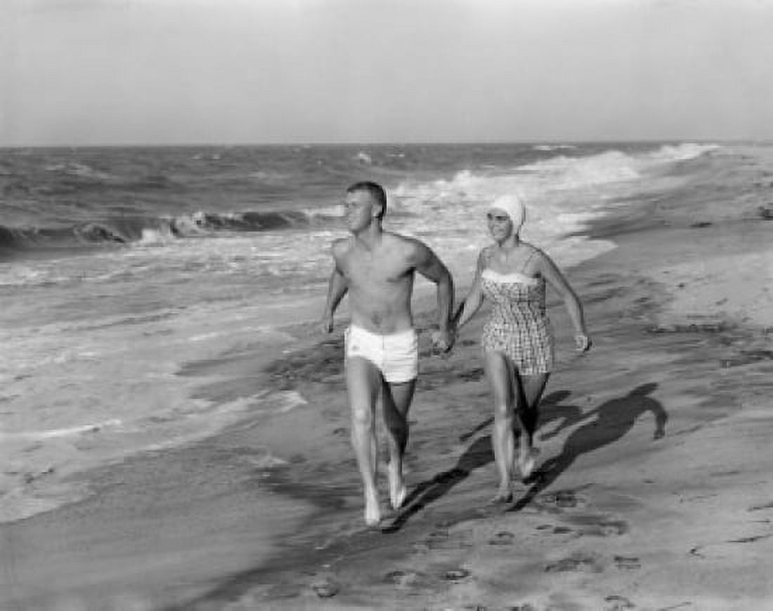 Young couple wearing swimming costumes walking on beach Canvas Art - (24 x 36)