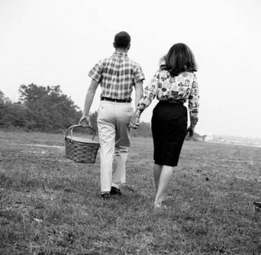 Young couple with picnic basket walking in field Canvas Art - (18 x 24)