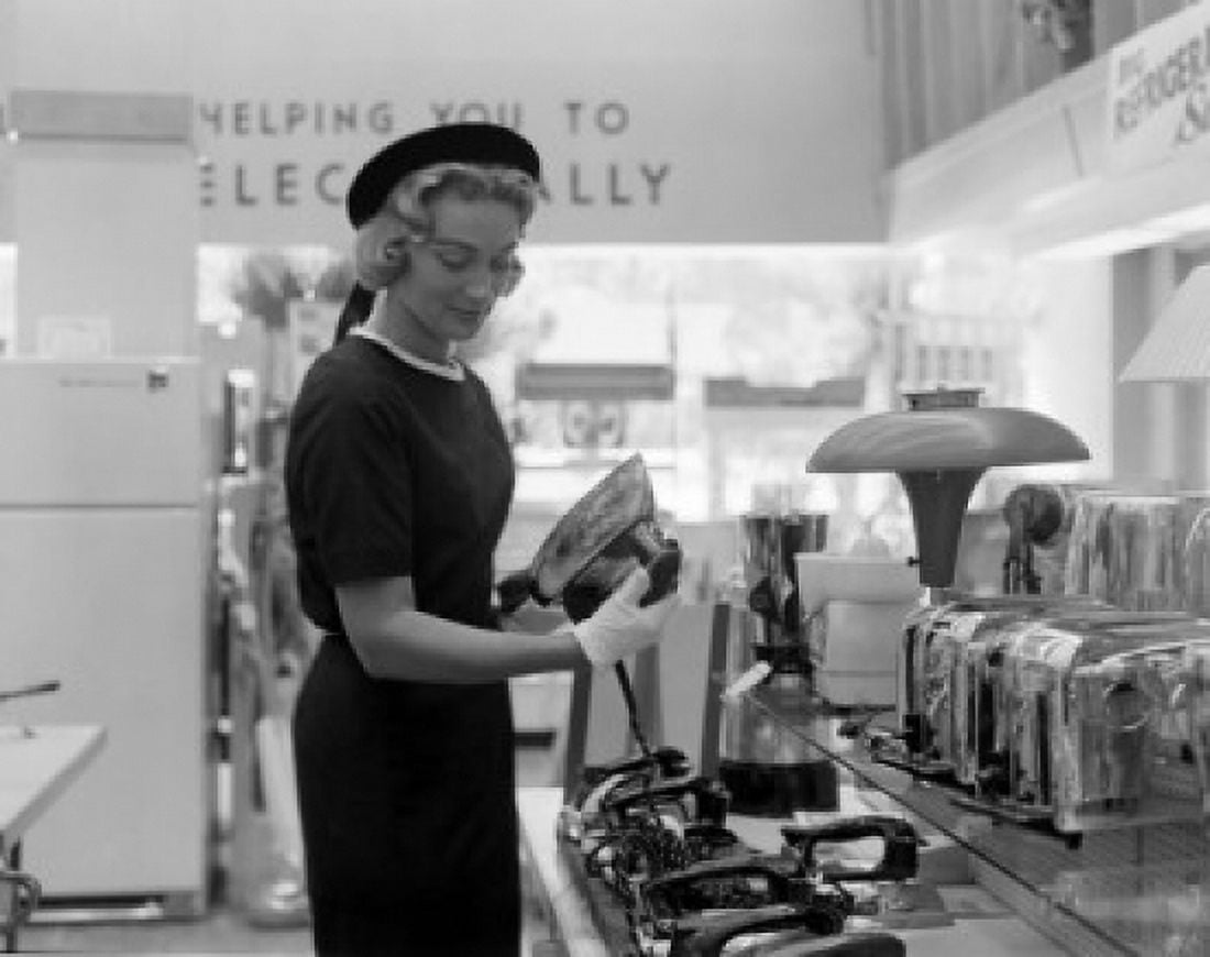 Young housewife examining iron on commercial display Canvas Art -  (18 x 24)