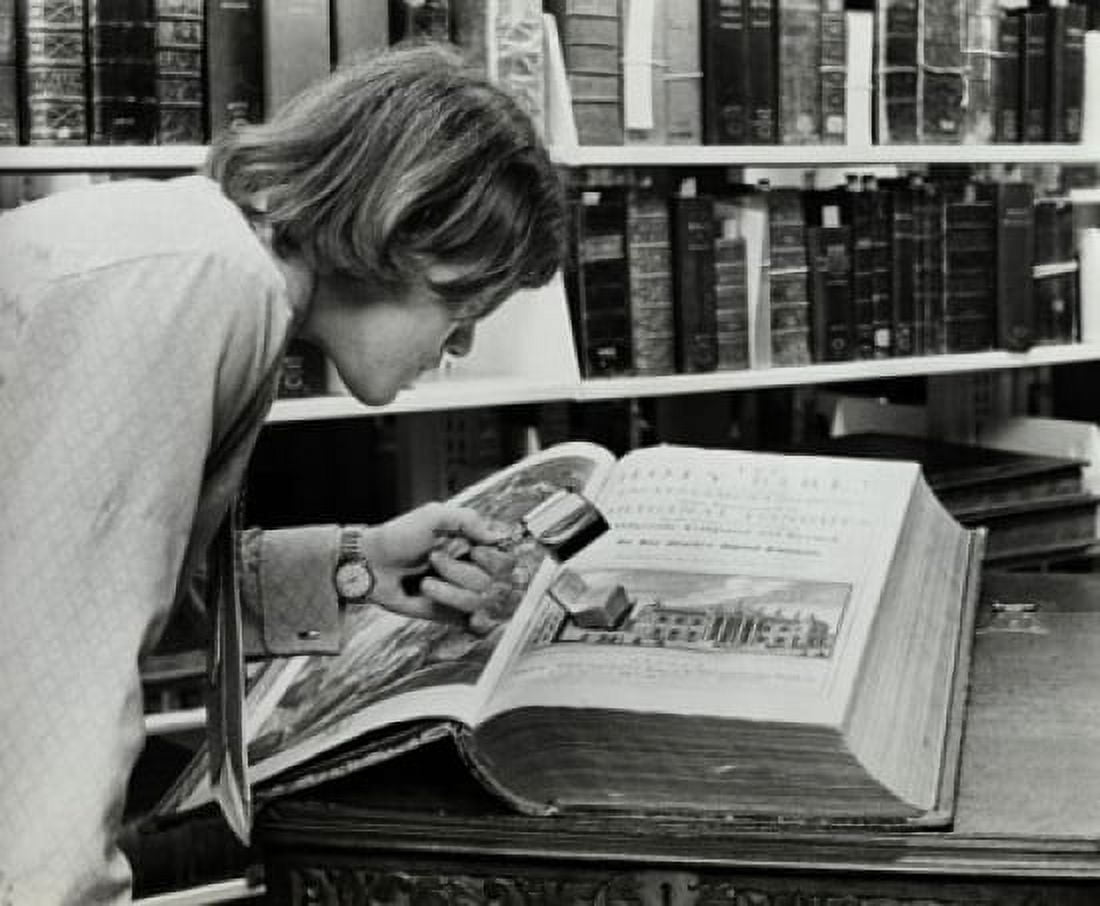 Young man examining a miniature Bible in a library Canvas Art - (24 x 36)