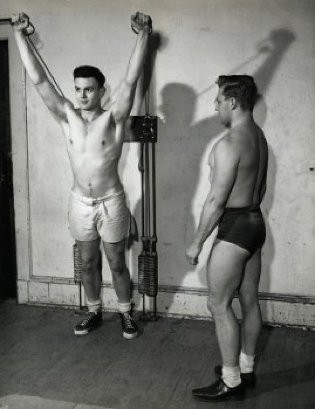 Young man exercising in a gym with another standing beside him Canvas Art - (18 x 24)