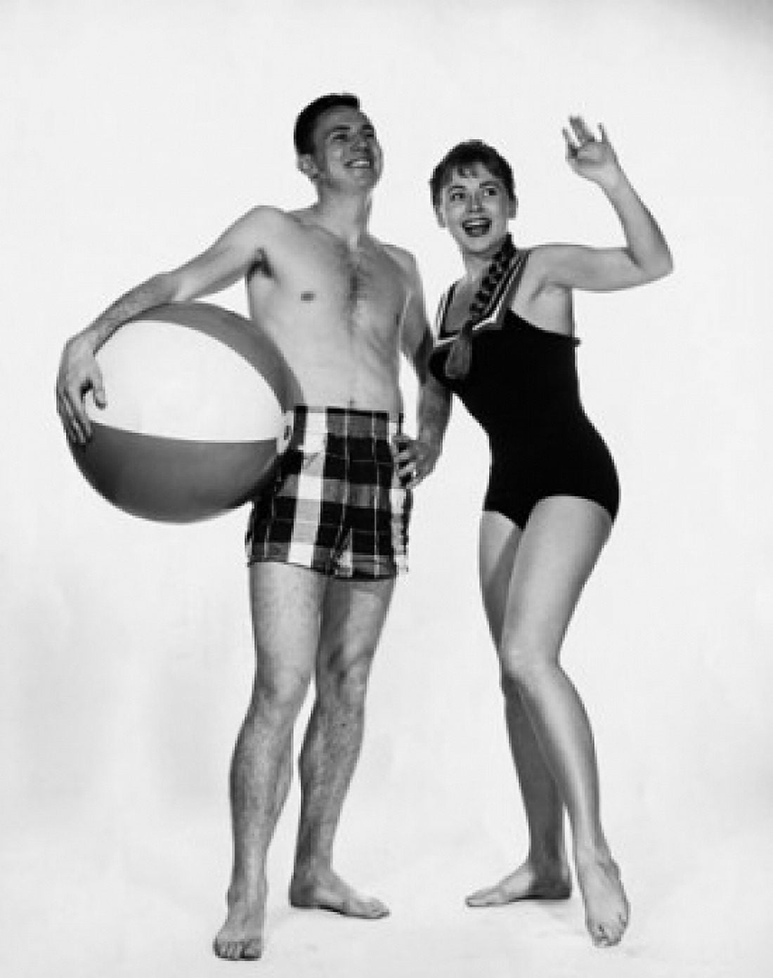 Young man holding a beach ball with a young woman waving Canvas Art - (18 x 24)