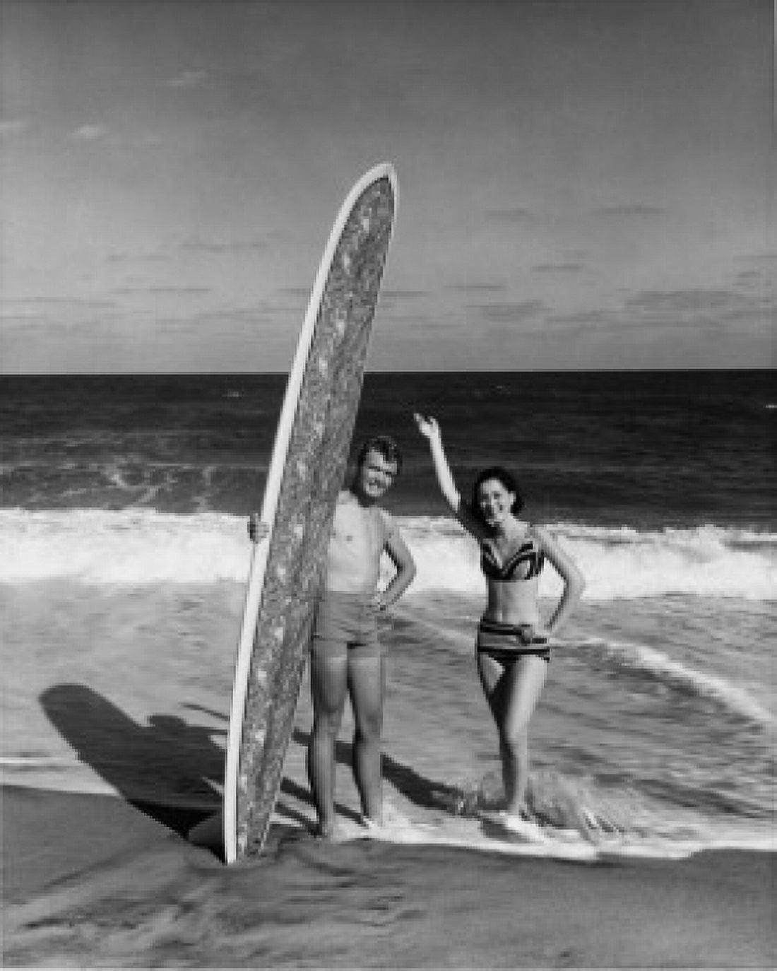 Young man holding surfboard on beach with young woman standing beside him Canvas Art - (18 x 24)