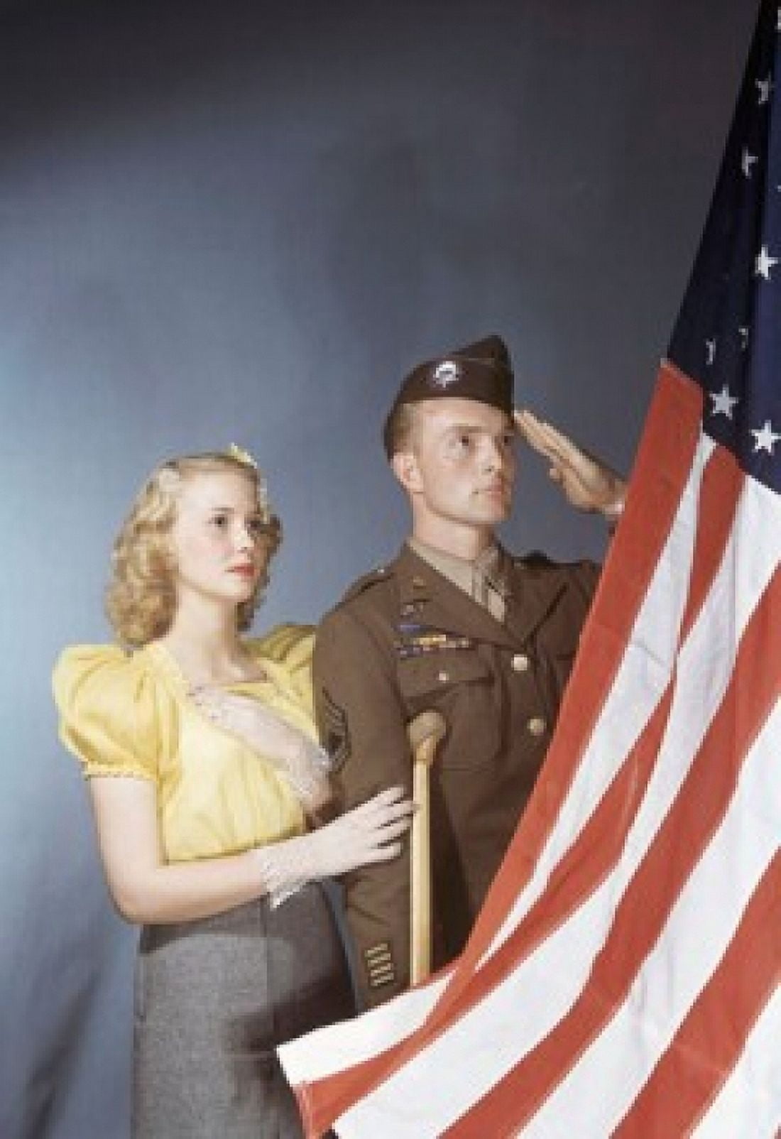 Young man saluting an American flag with a young woman standing beside him Canvas Art - (18 x 24)