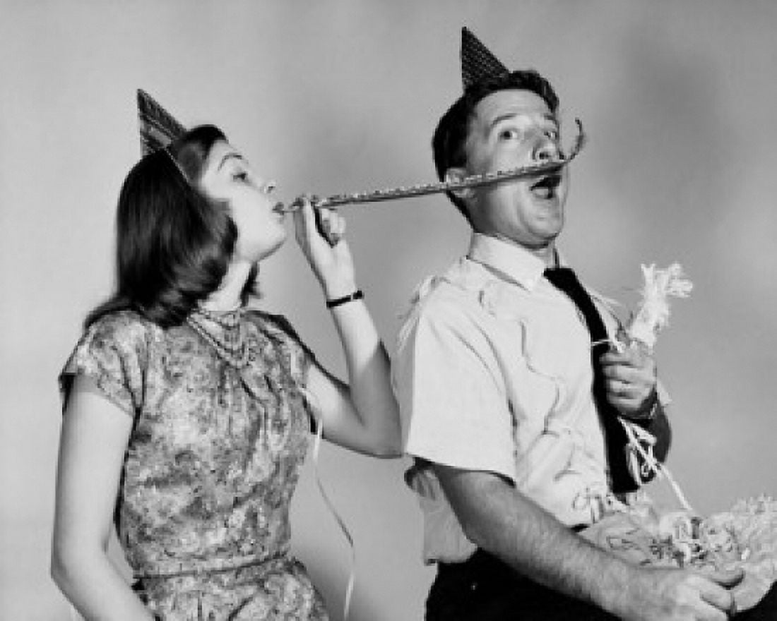 Young woman blowing a noisemaker near a young mans face Canvas Art - (18 x 24)